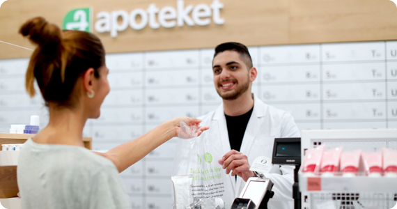 En kund får en påse av en apotekare